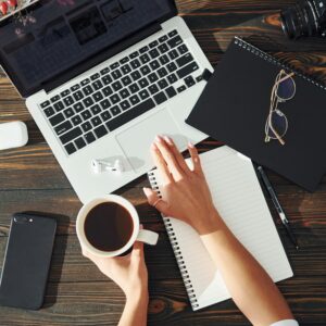 Top view. Young female freelancer working indoors in the office at daytime. Laptop and notepad